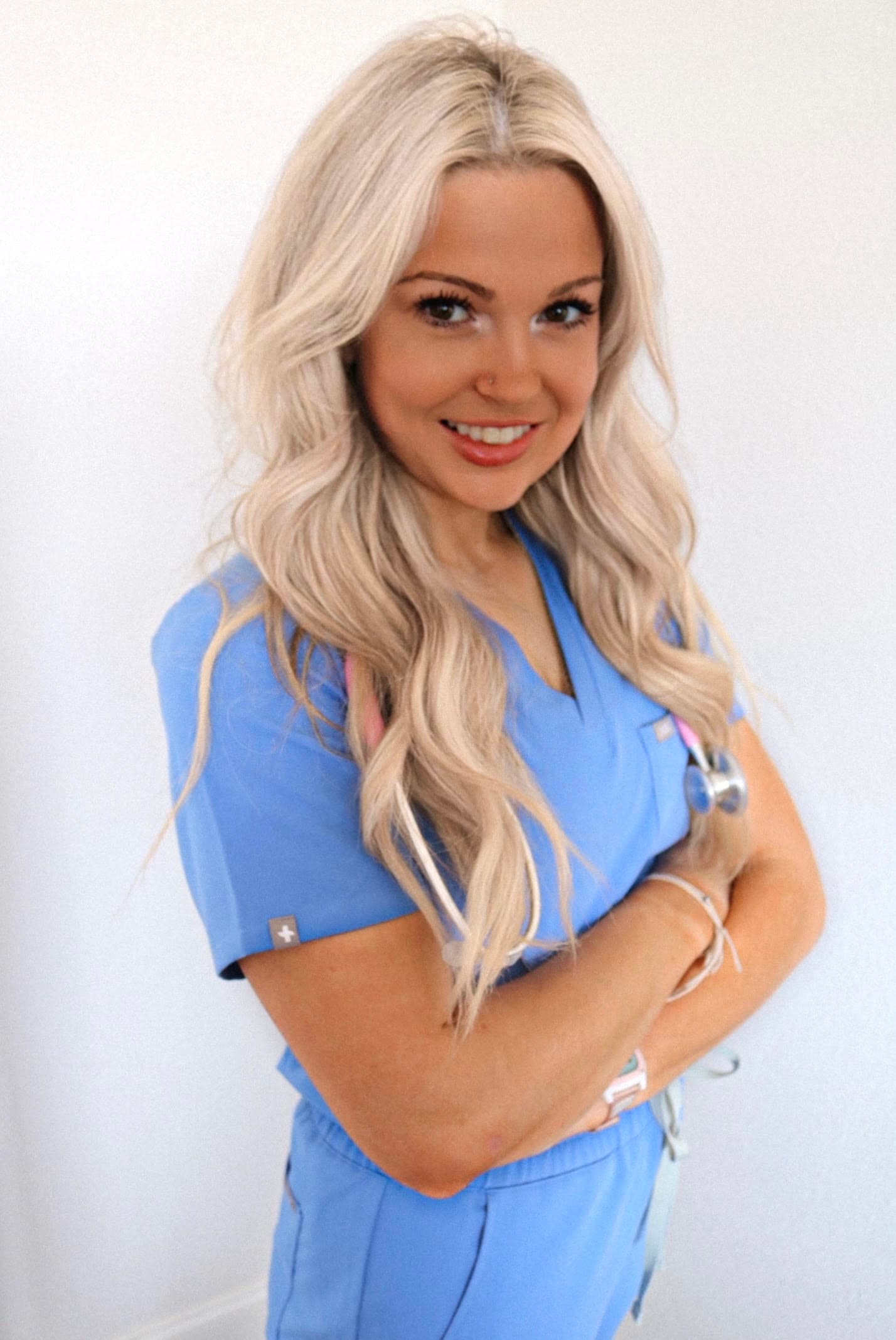 Dr. Kenzie Daniels, DC, smiling in blue scrubs with a stethoscope